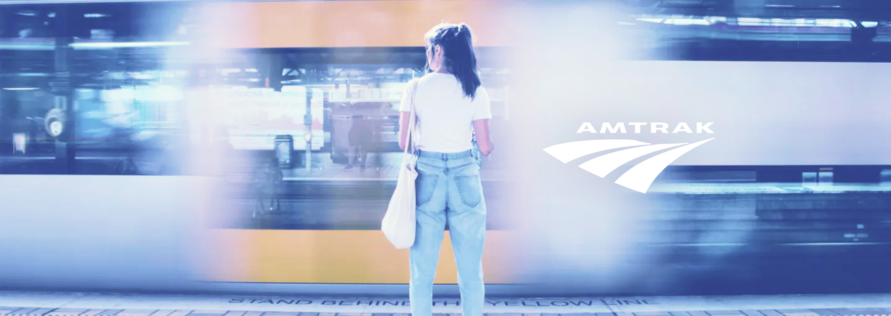 Woman standing in front of passing train with Amtrak logo next to her