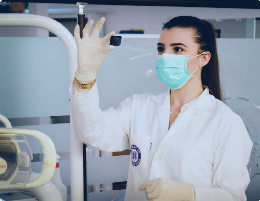 Lab technician with mask on holding up specimen to examine in lab room